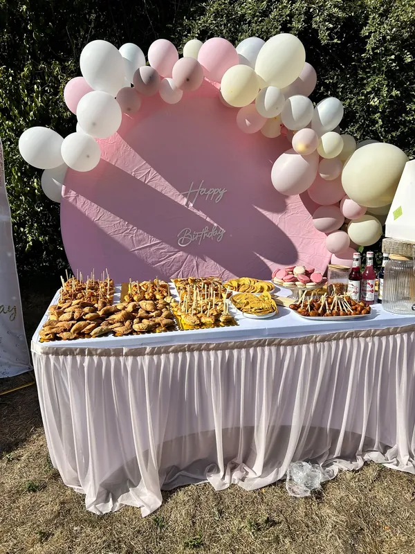 Buffet de mets salés avec arche de ballons et fond rose Happy Birthday
