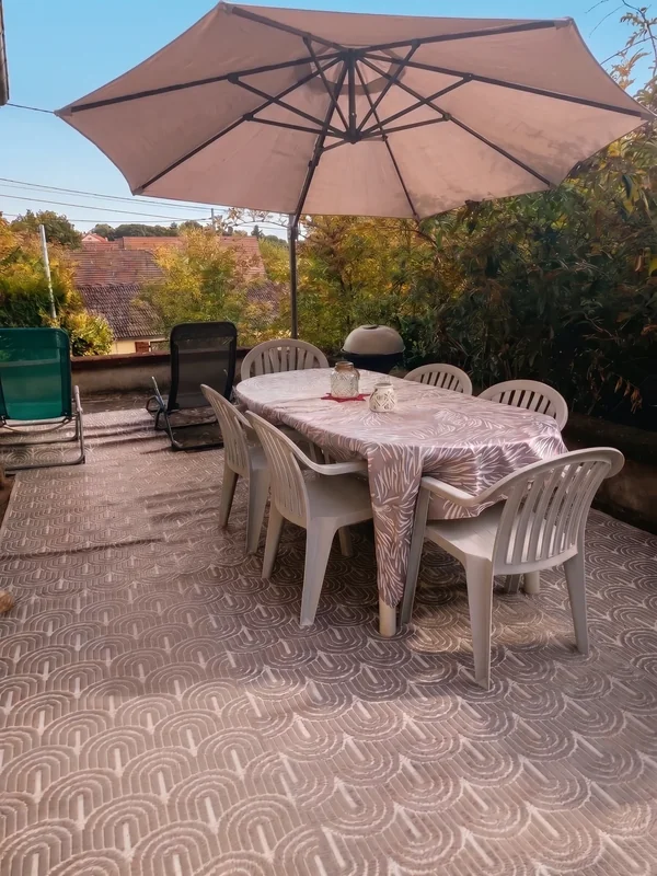 Terrasse avec grande table, chaises et parasol dans le jardin de Sarcelles