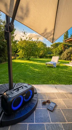 Enceinte Bluetooth posée sur la terrasse avec vue sur la pelouse et un transat