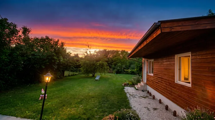 Jardin illuminé par un coucher de soleil spectaculaire avec la dépendance en bois et lampadaire