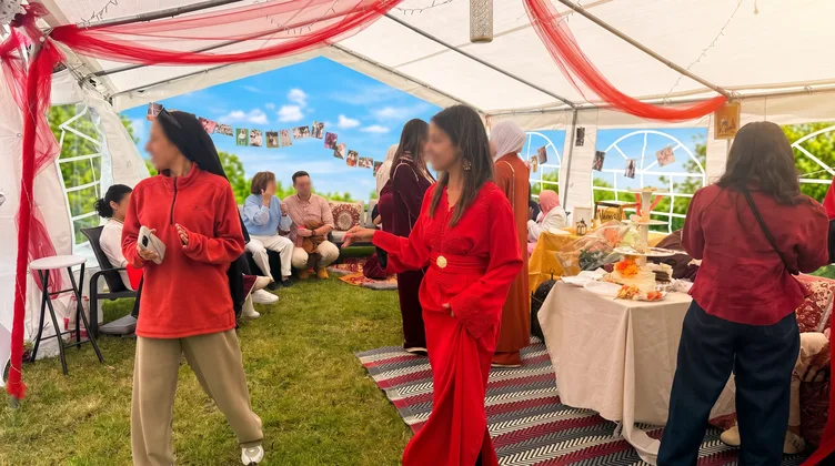 Fête sous chapiteau avec invités en tenues colorées, décoration festive et table de buffet