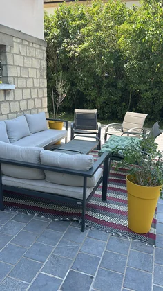Terrasse avec salon de jardin, canapé gris et tapis d'extérieur