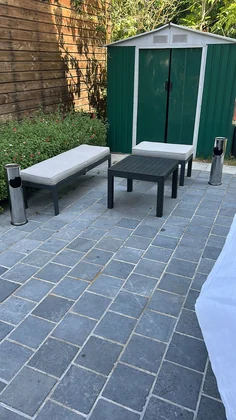 Banc de jardin contre le mur en pierre avec cabanon vert en arrière-plan