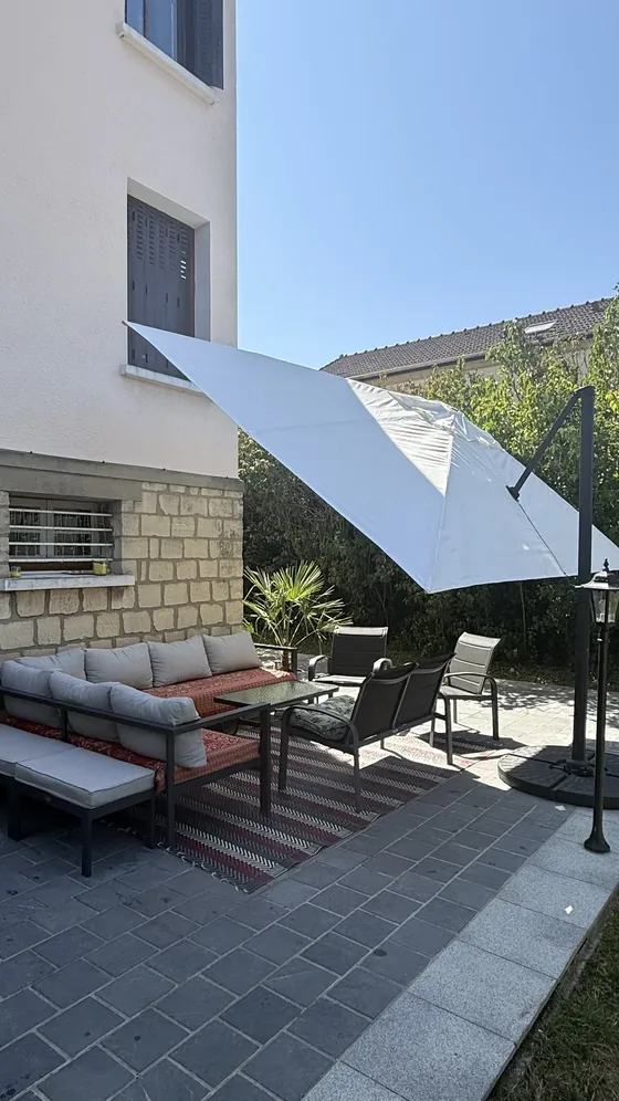 Salon de jardin sur la terrasse avec parasol déporté et lampadaire