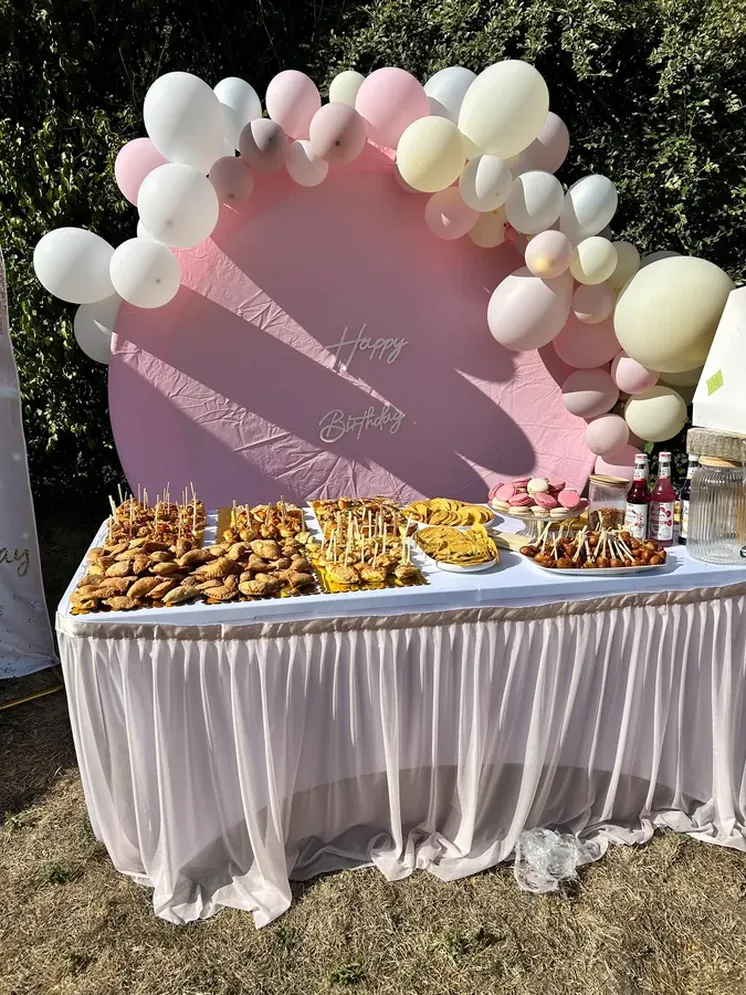 Buffet de mets salés avec arche de ballons et fond rose Happy Birthday